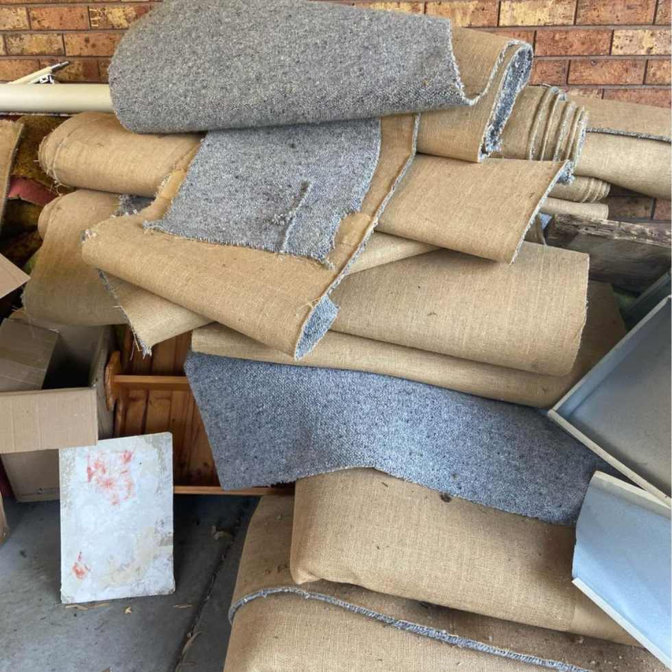 Rolled old carpet piled outside, ready for carpet removal and disposal