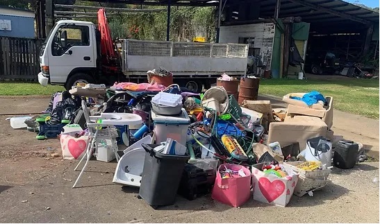 Household junk and tubs piled outdoors next to a truck, ready for garage and shed clean-up