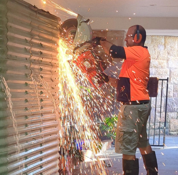 Junk Removers team cutting down a steel water tank for removal on the Coffs Coast
